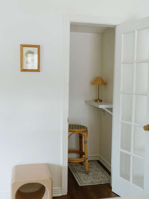 A phone booth with a rattan stool and a small lamp