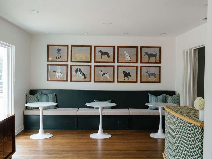 The Gather: a long green banquette with bistro tables beneath a wall of framed dog paintings
